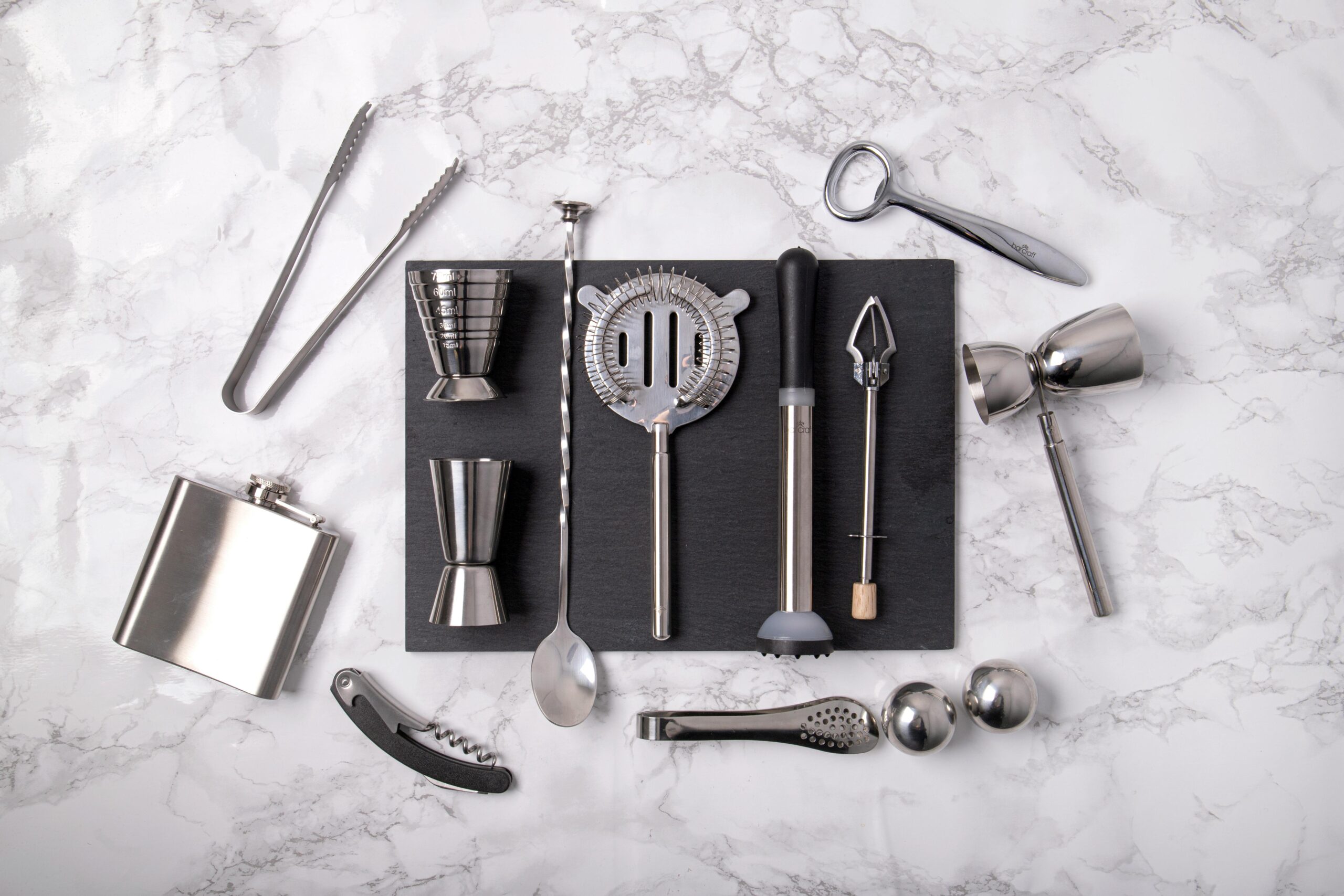 A flat lay of professional bartending tools arranged on a marble surface, ideal for mixology enthusiasts.